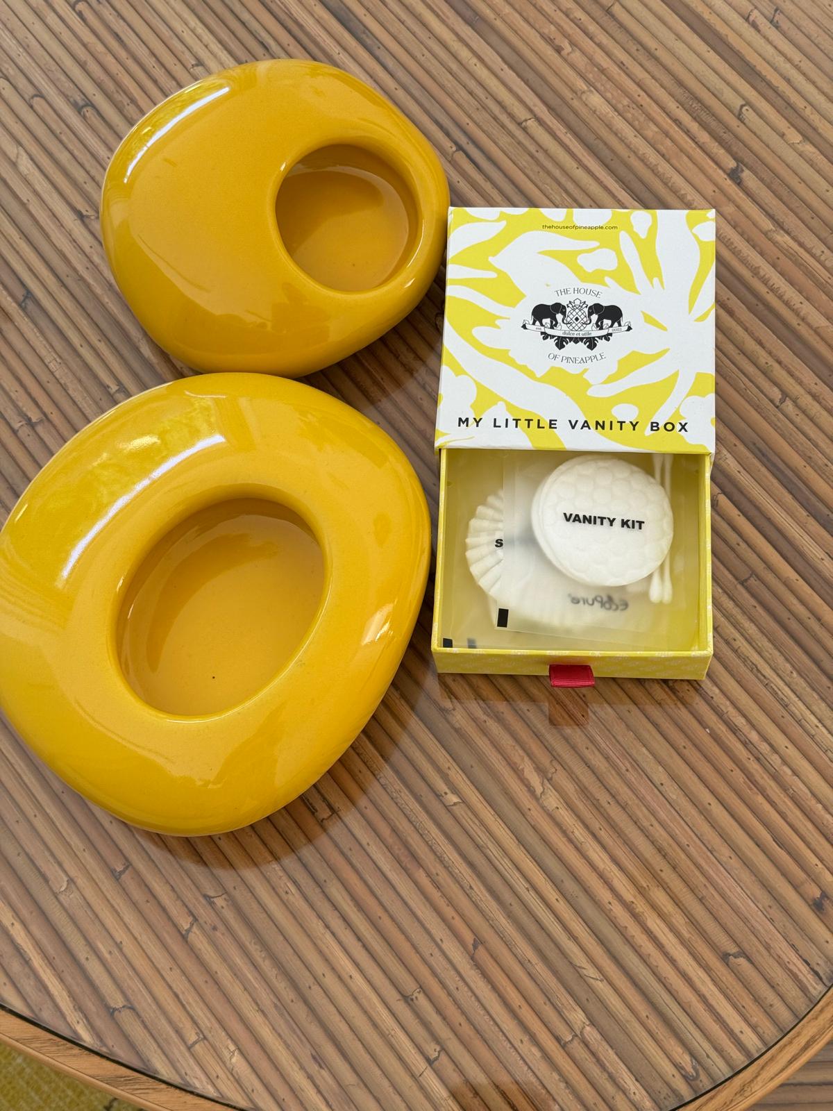 Vanity kit and yellow ceramic decor pieces on a wooden table.