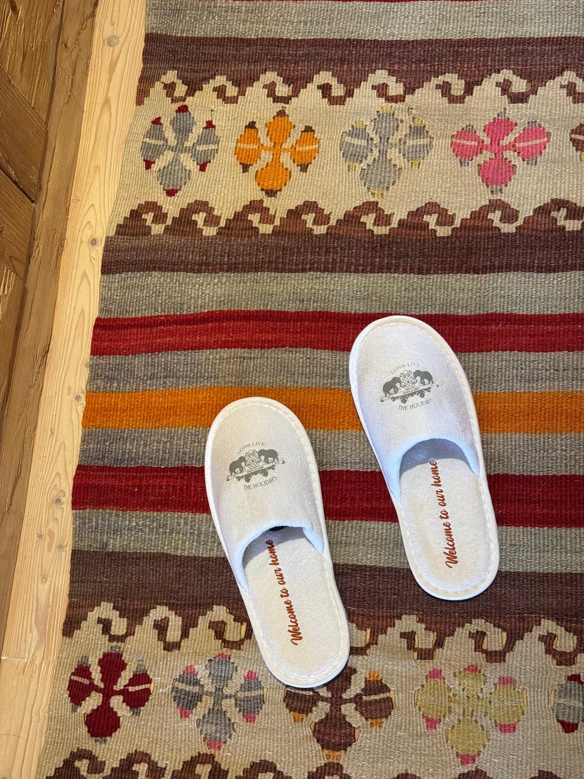 White slippers on a colourful patterned rug with red and orange stripes.